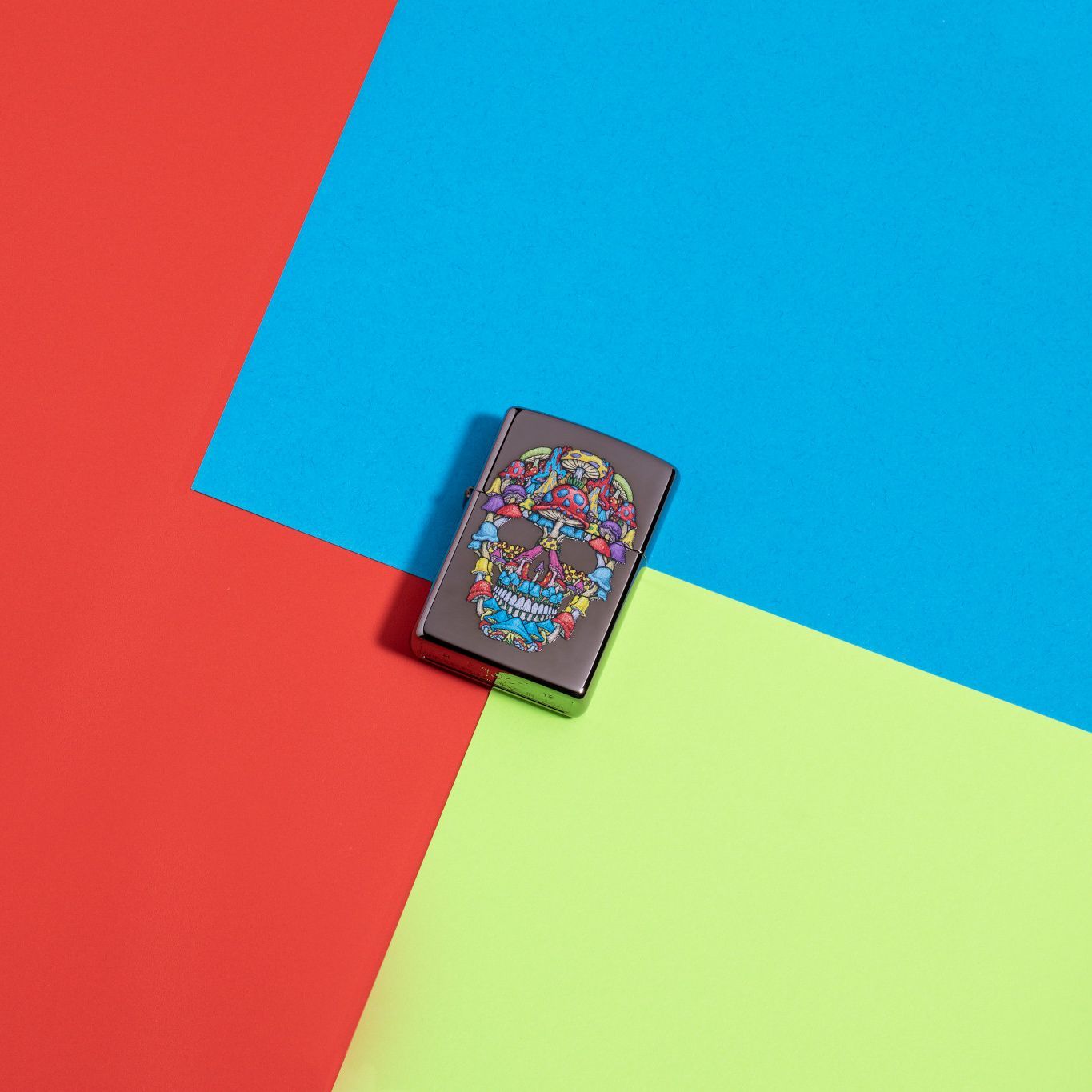 Lifestyle image of Mushroom Skull Design Black Ice Windproof Lighter laying flat on neon multicolored background