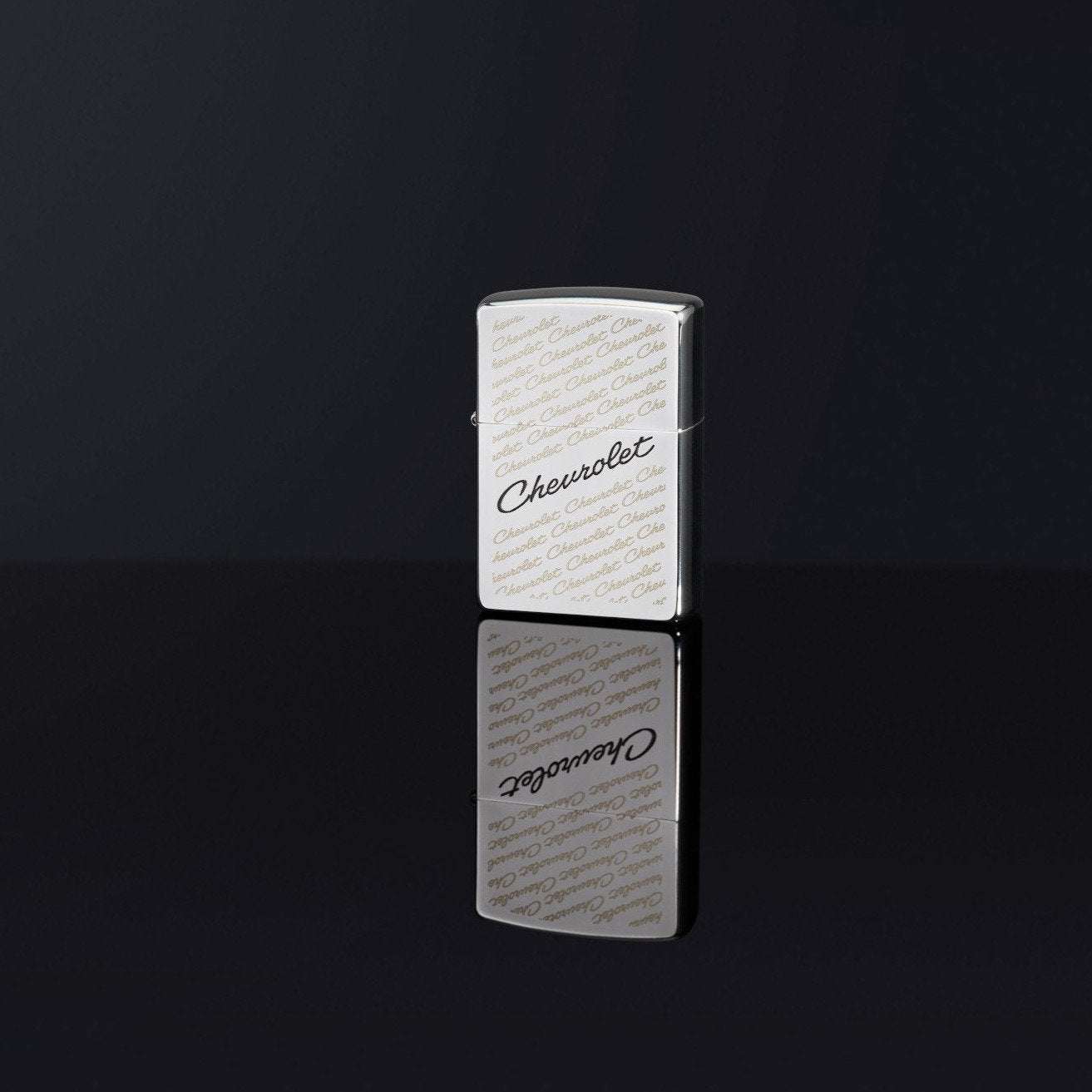 Lifestyle image of Chevrolet® High Polish Chrome Windproof Lighter standing in a black reflective background