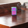 Lifestyle image of Cannabis Leaf Design Multi Color Windproof Lighter standing on a table with an incense burner in the background.